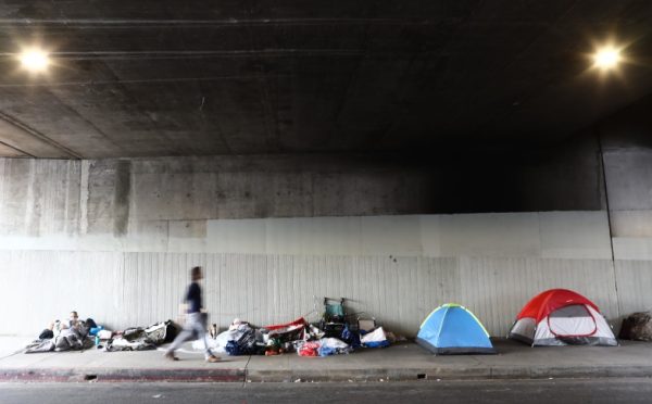 LOS ANGELES, CALIFORNIA - JUNE 05:  A man walks past a homeless encampment beneath an overpass on June 5, 2019 in Los Angeles, California. The homeless population count in Los Angeles County leaped 12 percent in the past year to almost 59,000, according to officials.  (Photo by Mario Tama/Getty Images)