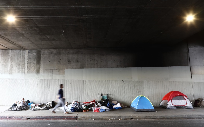 LOS ANGELES, CALIFORNIA - JUNE 05:  A man walks past a homeless encampment beneath an overpass on June 5, 2019 in Los Angeles, California. The homeless population count in Los Angeles County leaped 12 percent in the past year to almost 59,000, according to officials.  (Photo by Mario Tama/Getty Images)